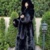 Full-length black faux fur coat with oversized hood, worn outdoors, showcasing a luxurious winter fashion look with elegant and dramatic style.